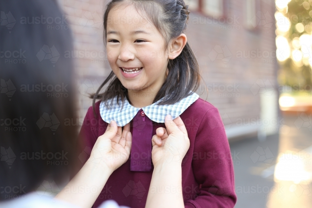 Mother fixing her daughter's school uniform collar - Australian Stock Image