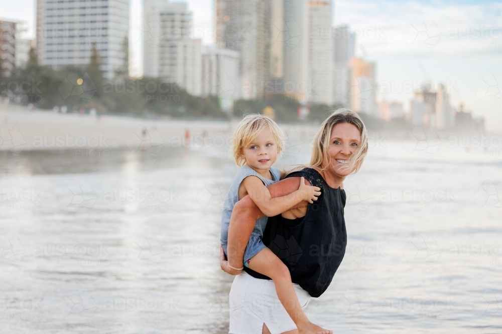 Mother giving son piggy back ride on Main Beach, Surfers Paradise on the Gold Coast - Australian Stock Image