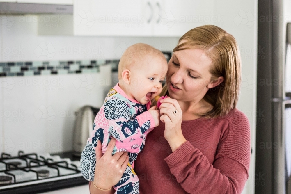 Mother holding baby and giving dummy - Australian Stock Image