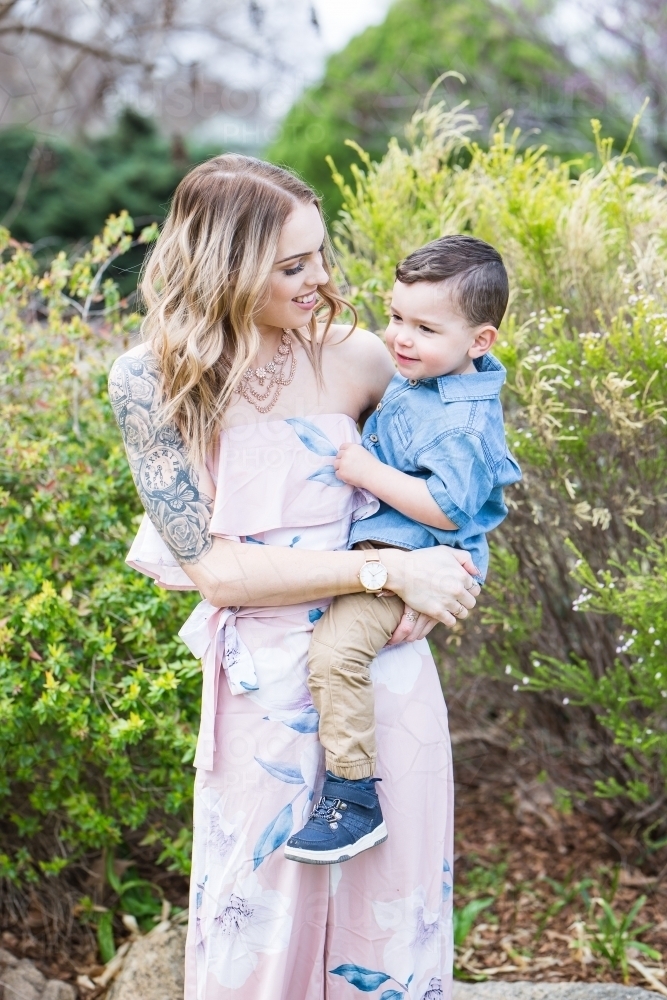 Mother holding mixed race aboriginal caucasian child on hip smiling - Australian Stock Image