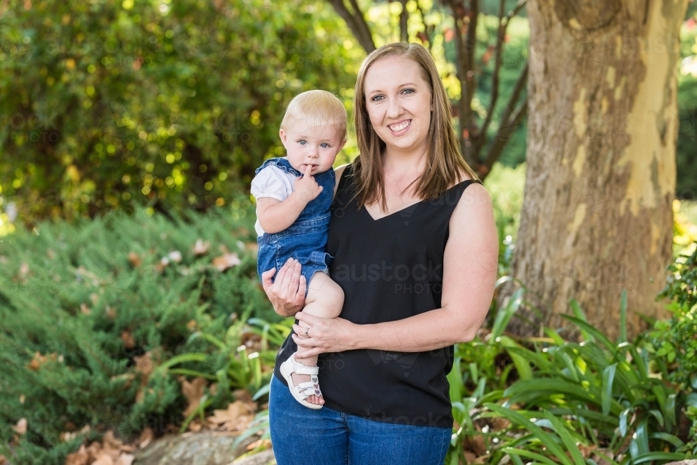 Image of Mother holding toddler child on hip in garden Austockphoto