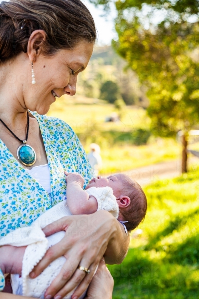 Mother looking at her newborn daughter smiling outside - Australian Stock Image