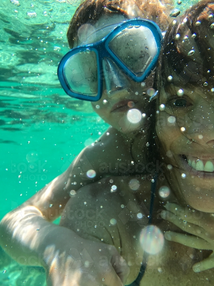 Mother with son on her back both wearing a snorkeling mask underwater - Australian Stock Image