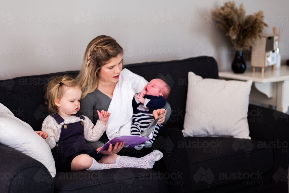 mother with two children baby and toddler reading books - Australian Stock Image