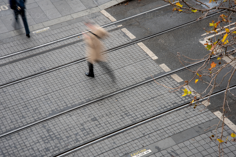 Motion blurred pedestrian crossing tram tracks seen from above - Australian Stock Image