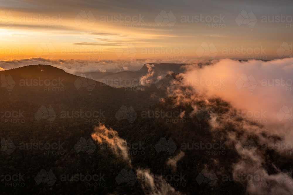 mountain landscape with morning golden light above low clouds - Australian Stock Image