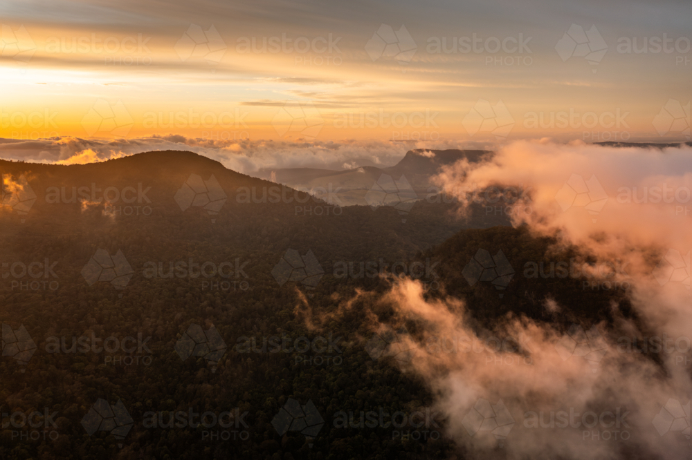 mountain landscape with morning golden light above low clouds - Australian Stock Image