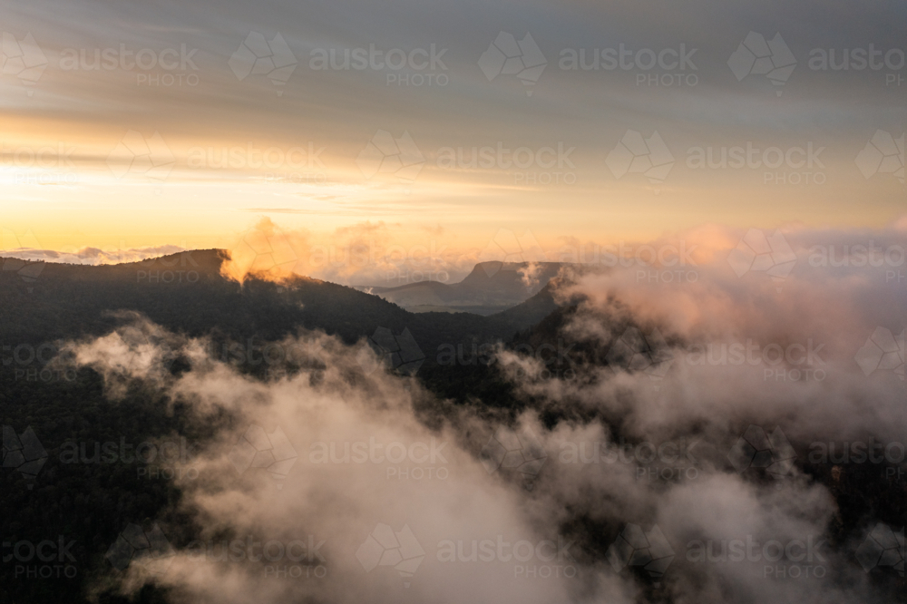 mountain landscape with morning golden light above low clouds - Australian Stock Image