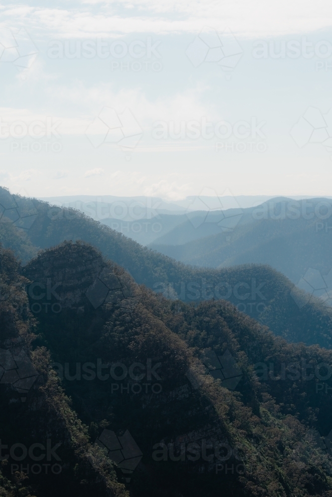 Mountain layers through the valley at Kanangra Walls Lookout on a sunny day - Australian Stock Image