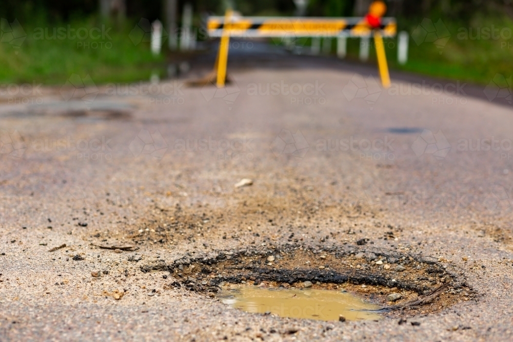 Muddy pot hole in gravel road closed because of flooding - Australian Stock Image