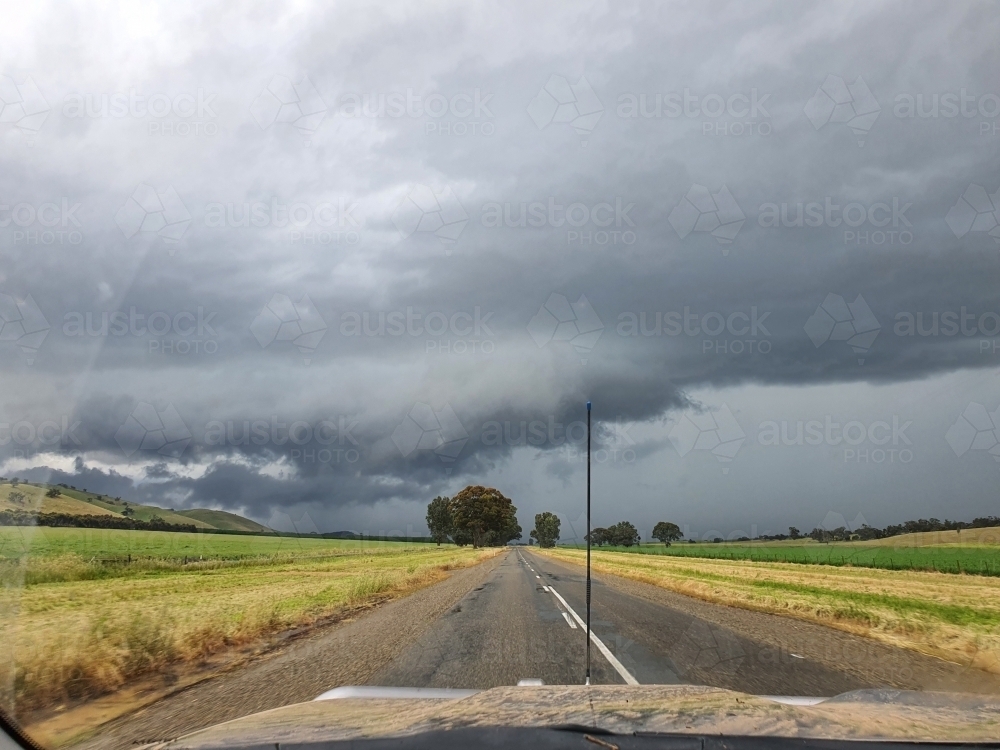 muddy vehicle on country road with stormy skies - Australian Stock Image