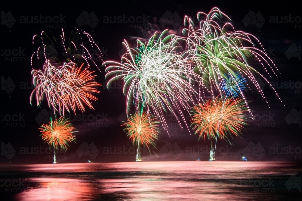 Multi coloured fireworks exploding over an ocean in the night sky. - Australian Stock Image