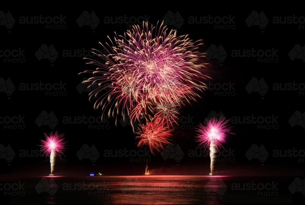 Multi coloured fireworks exploding over an ocean in the night sky. - Australian Stock Image