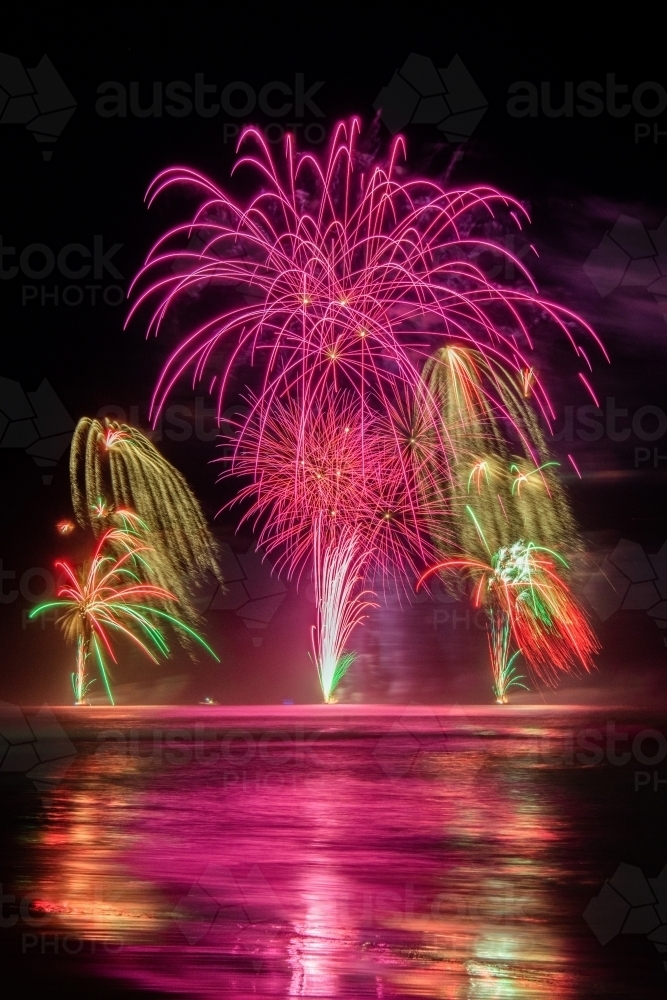 Multi coloured fireworks exploding over an ocean in the night sky. - Australian Stock Image