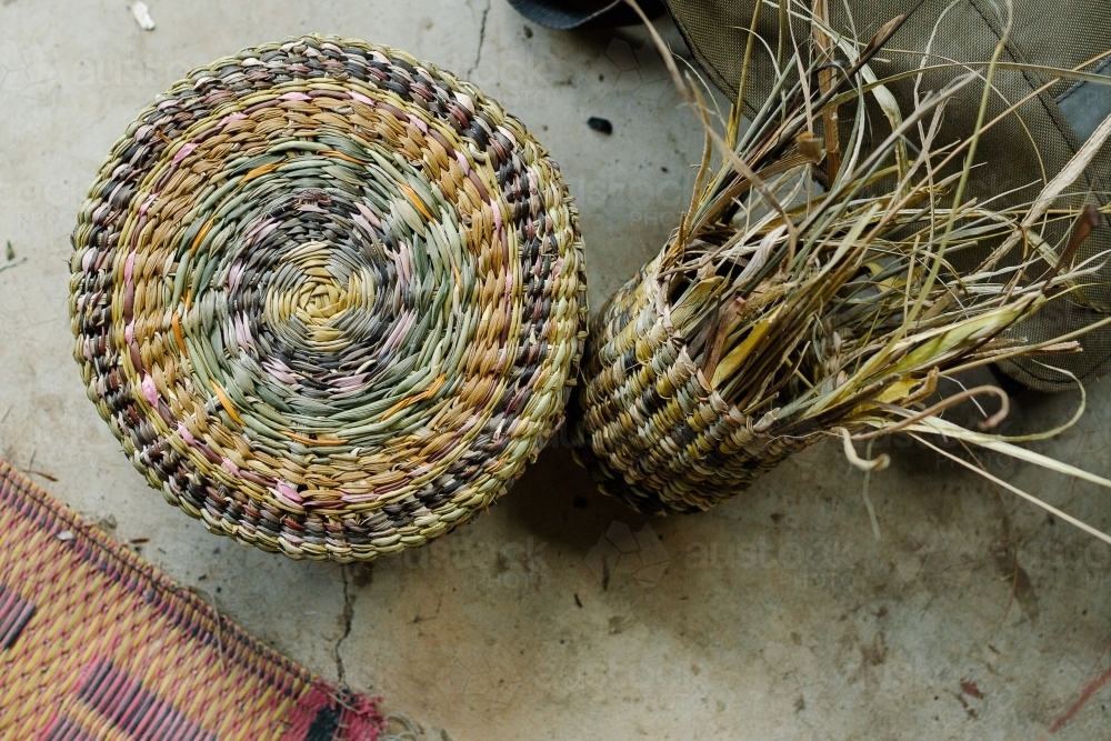 Multicolored woven basket lying on the concrete floor. - Australian Stock Image