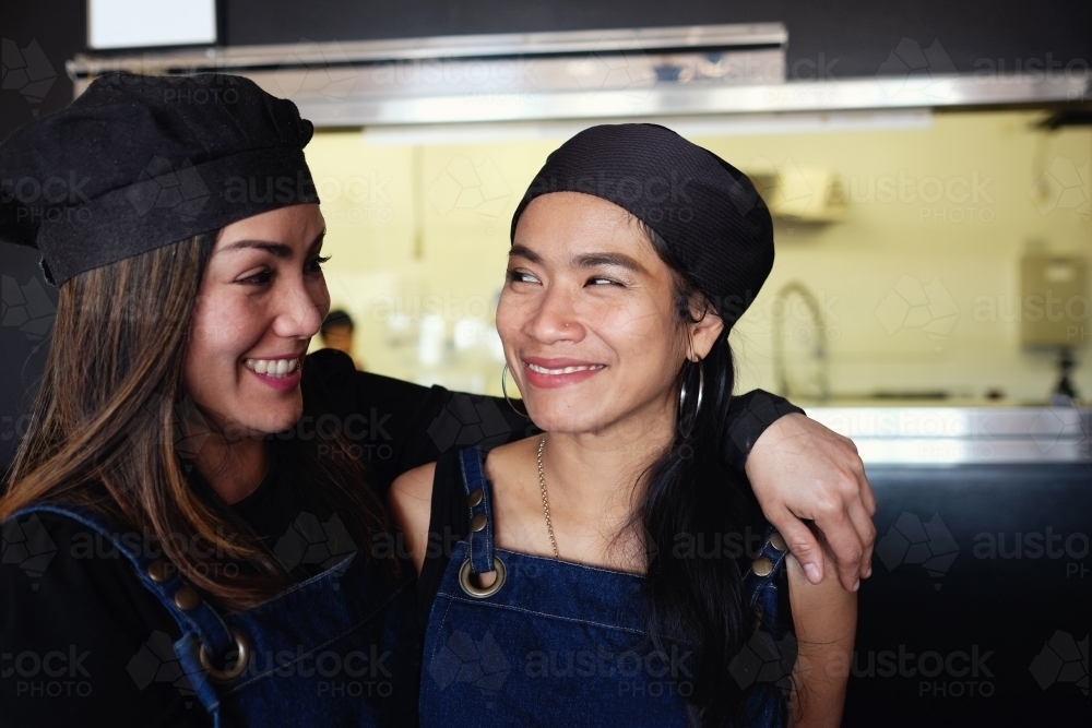 Multicultural Asian small business owners/ waitress in Thai restaurant - Australian Stock Image