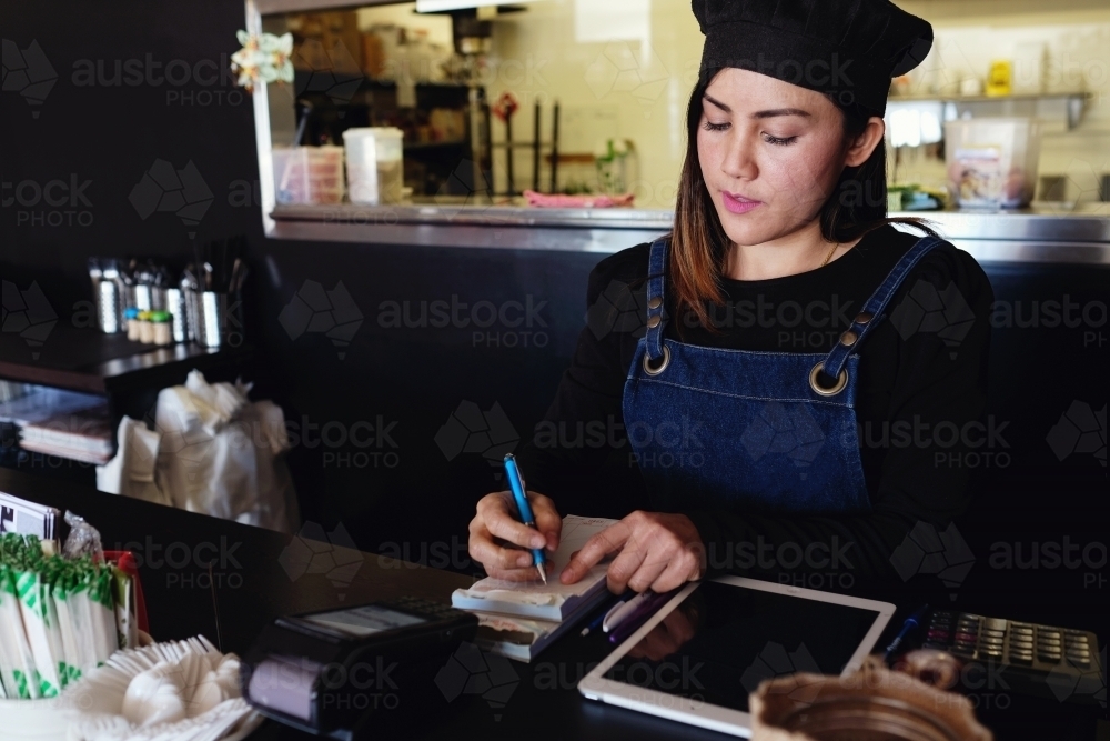 Multicultural Asian waitress taking order at Thai restaurant - Australian Stock Image