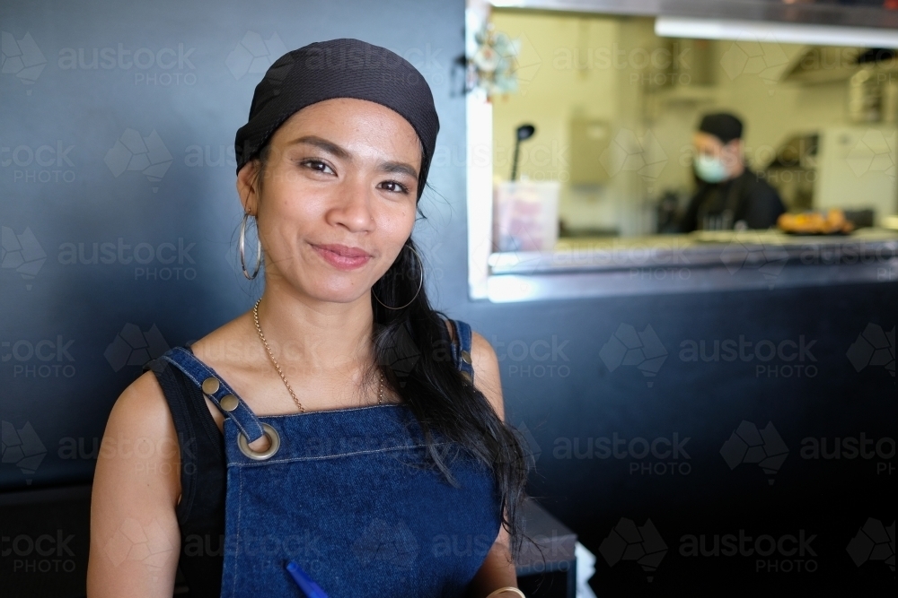 Multicultural Asian waitress taking order at Thai restaurant - Australian Stock Image