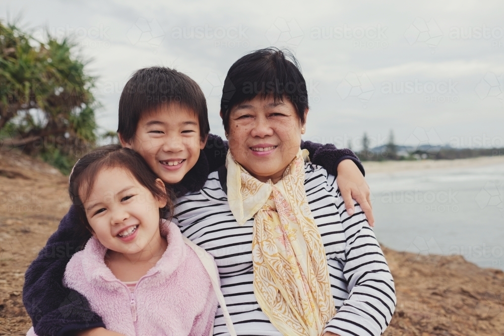 Multicultural grandchildren hug Asian grandmother - Australian Stock Image