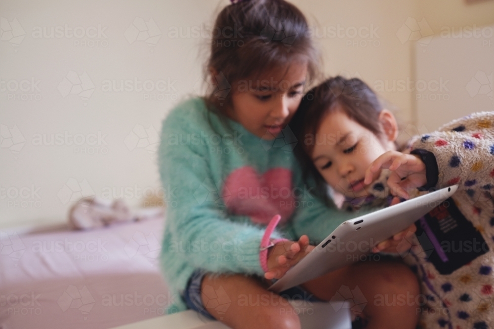 Multicultural kids using tablet in bedroom - Australian Stock Image