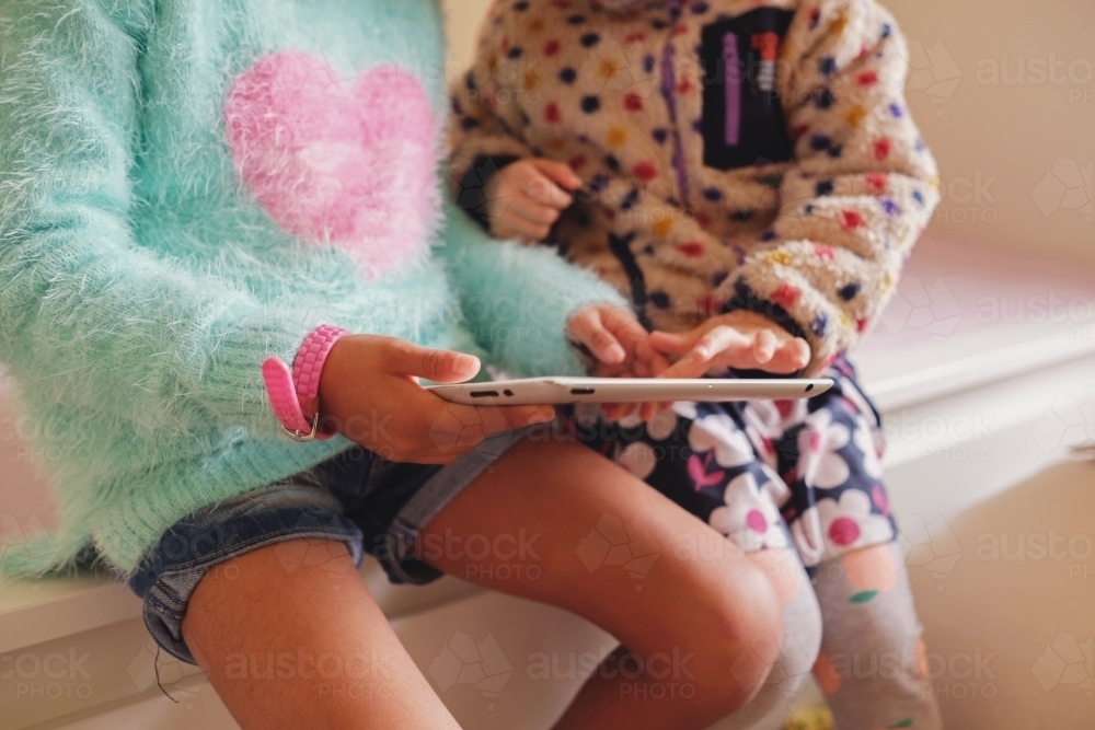 Multicultural kids using tablet in bedroom - Australian Stock Image