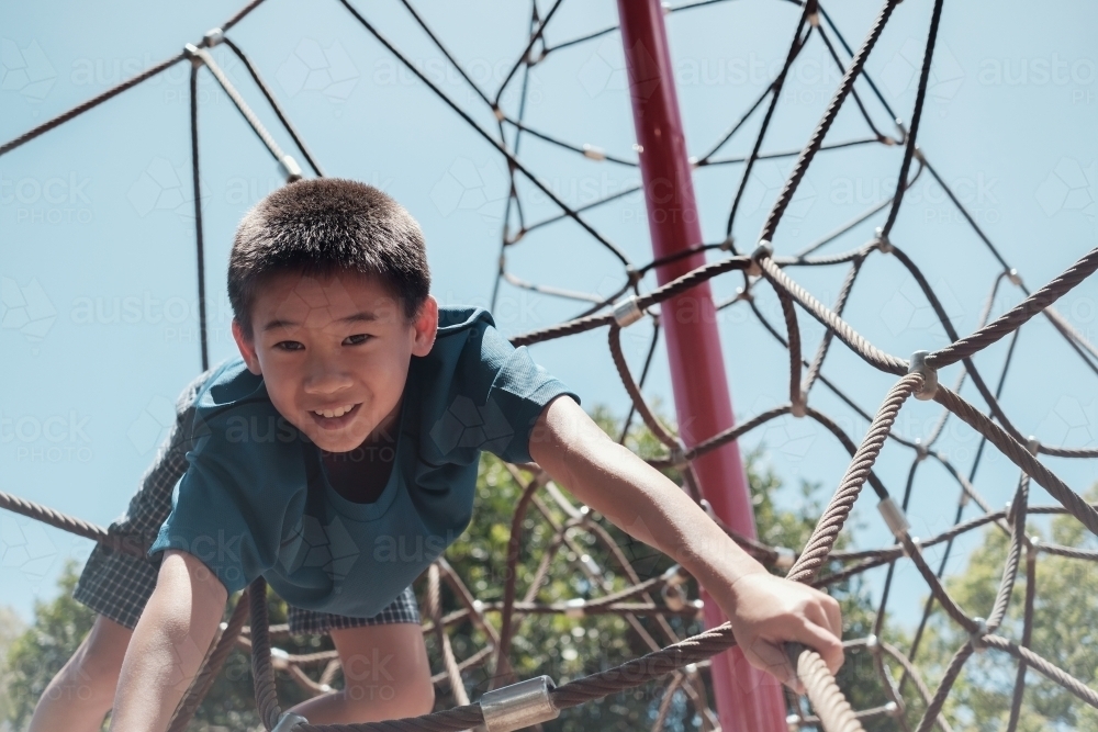 multicultural preteen boy having fun at playground - Australian Stock Image