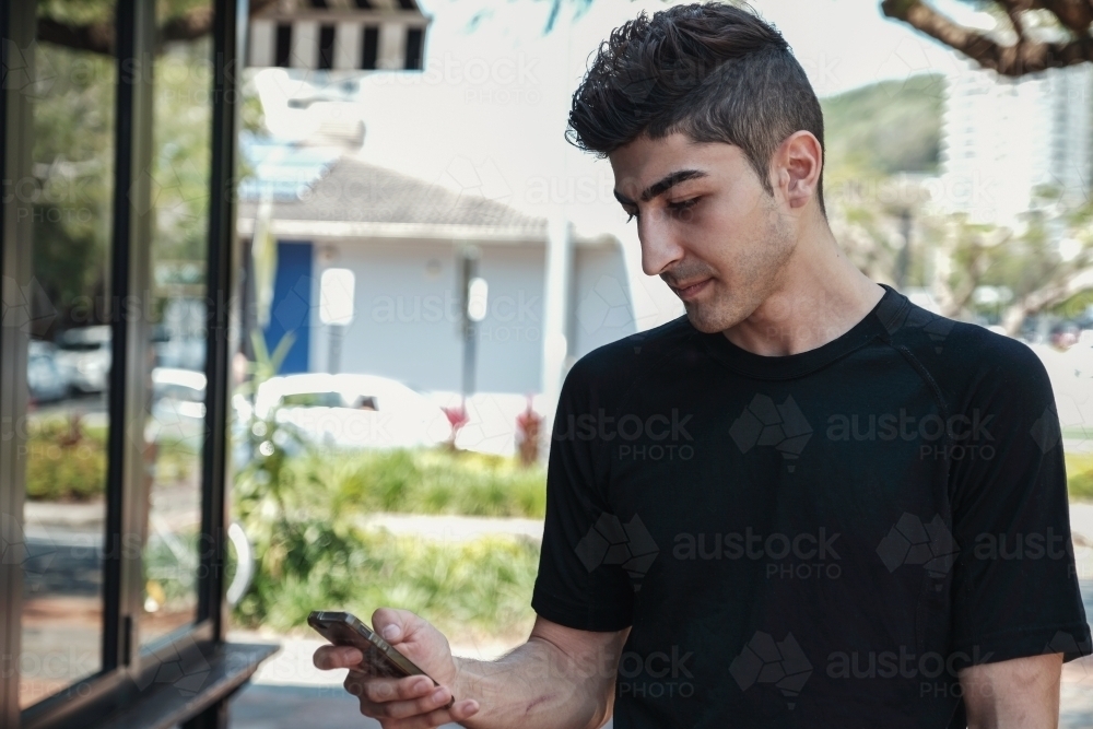 multicultural young adult man using smartphone - Australian Stock Image