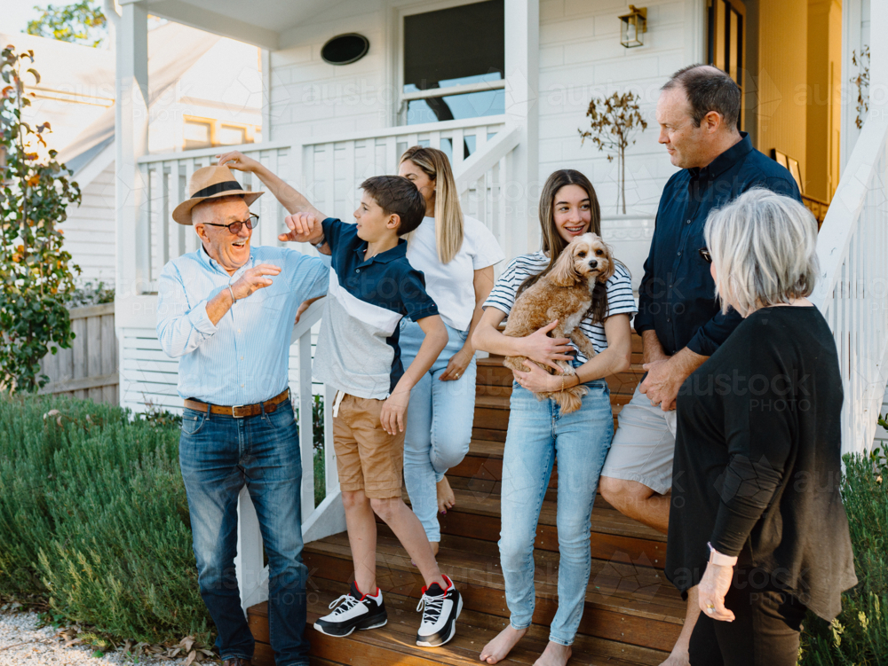 Multigeneration family standing on the steps in front of their house. - Australian Stock Image