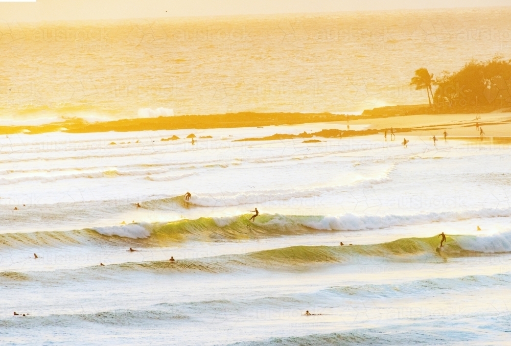 Multiple surfers riding waves during the early morning. - Australian Stock Image