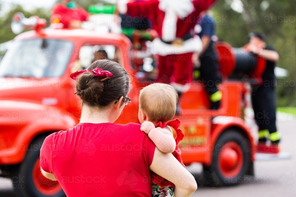 mum and baby waving to Santa Claus on the fire truck at Christmas time lolly run - Australian Stock Image