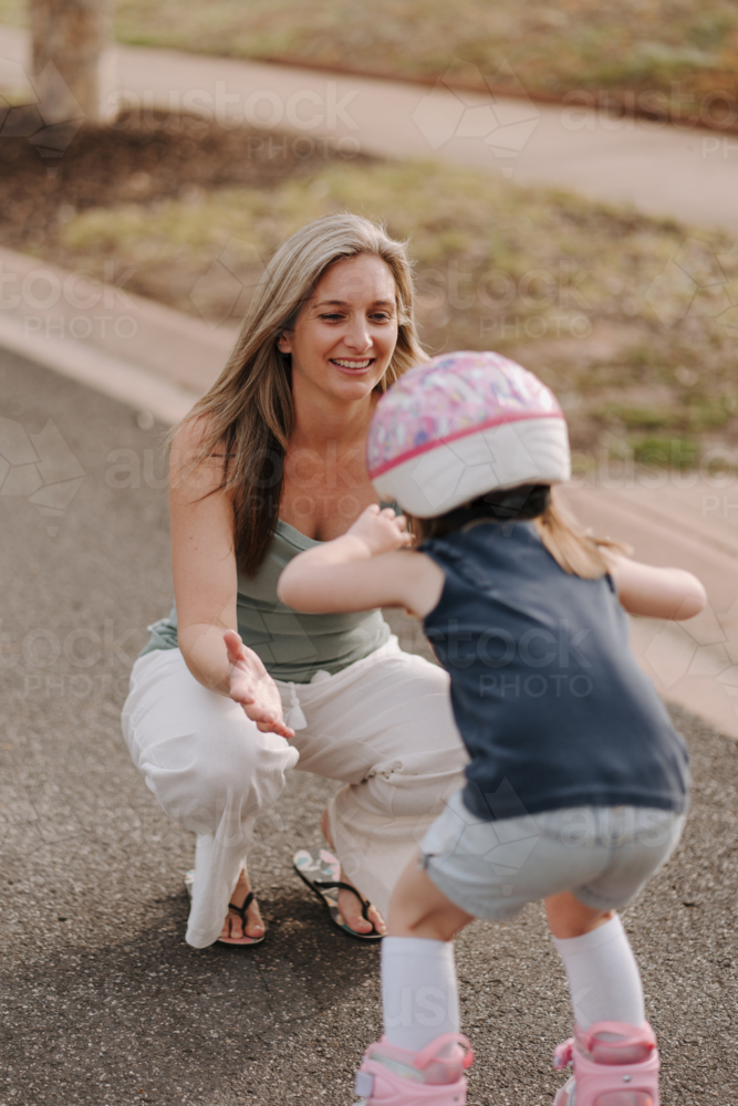 Mum with daughter on roller blades on the street. - Australian Stock Image