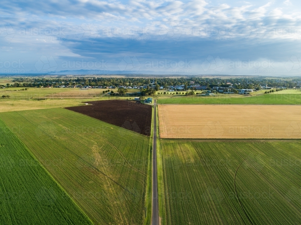 narrow country road through sunlit rural farm paddocks in summer - Australian Stock Image