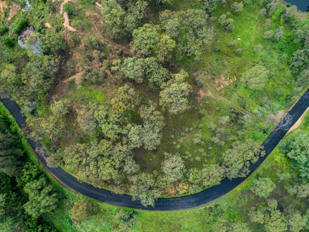 Narrow road curving through green paddocks and trees - Australian Stock Image