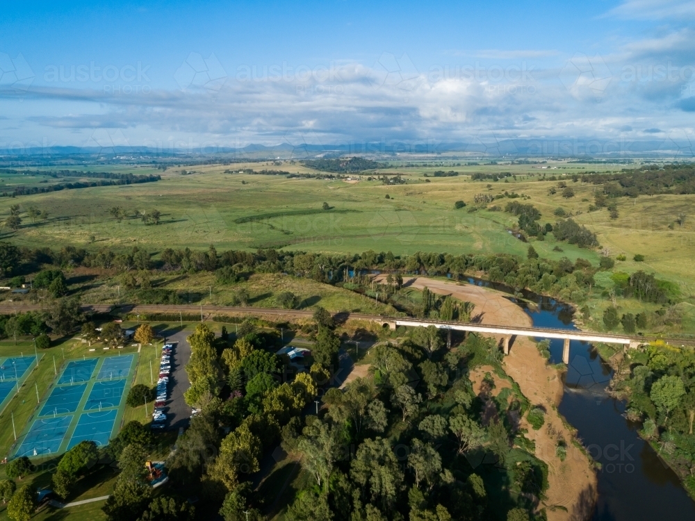 Netball courts, Rose Point Park and railway bridge over Hunter River with farm paddock beyond - Australian Stock Image