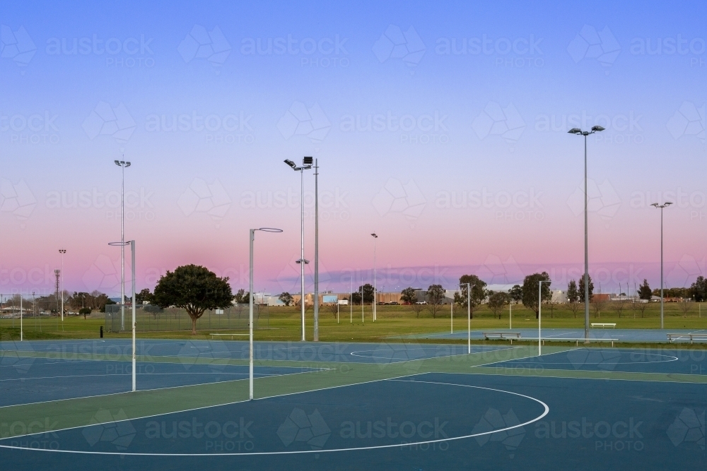 Netball hoop at empty community sports ground in dusk light - Australian Stock Image