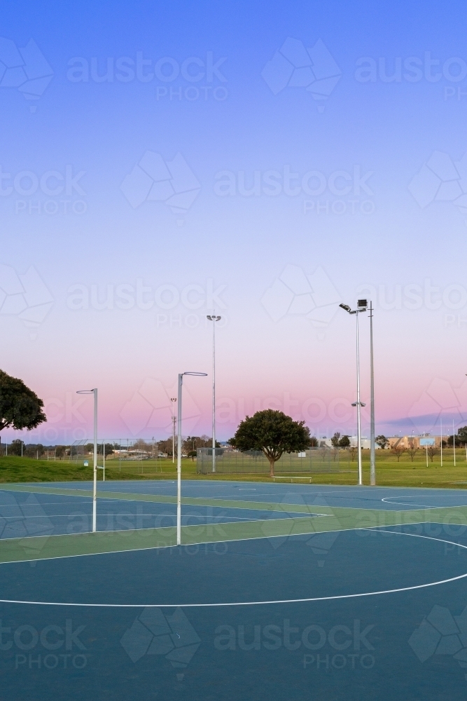 Netball hoop at empty community sports ground in dusk light - Australian Stock Image