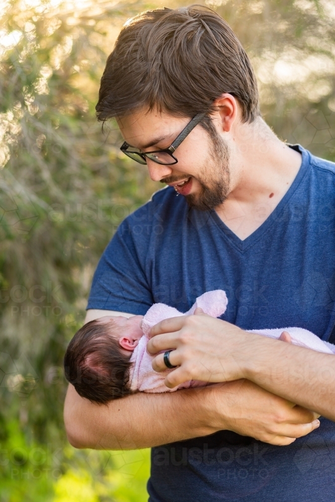 New dad holding his sleeping newborn baby daughter - Australian Stock Image