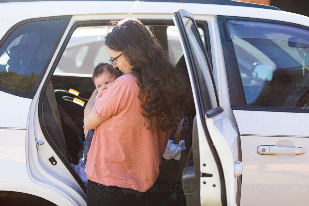 New mum putting baby in car to go out and about with newborn - Australian Stock Image