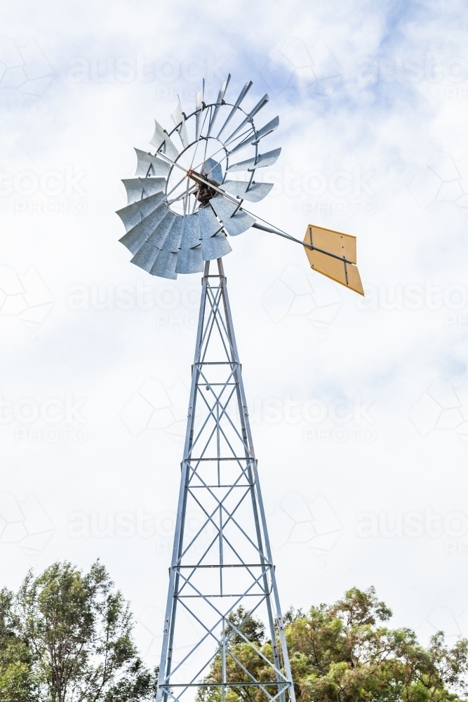 New yellow tail windmill against bright sky with clouds - Australian Stock Image