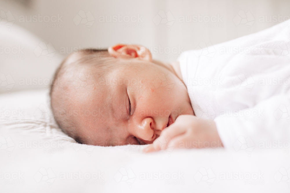 Newborn baby boy sleeping on his tummy on the bed. - Australian Stock Image