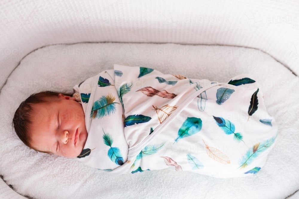 Newborn baby wrapped up in blanket in bassinet asleep - Australian Stock Image