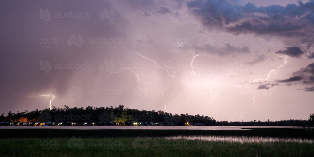 Night time lightning storm over lake and cabins - Australian Stock Image