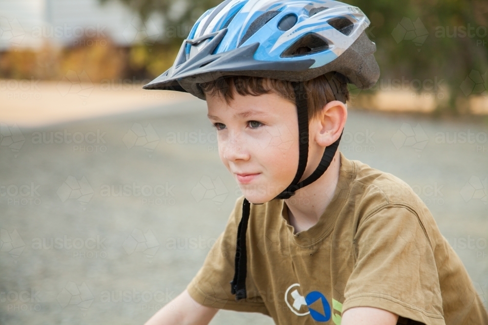 Nine year old boy riding his bicycle at home with helmet on - Australian Stock Image