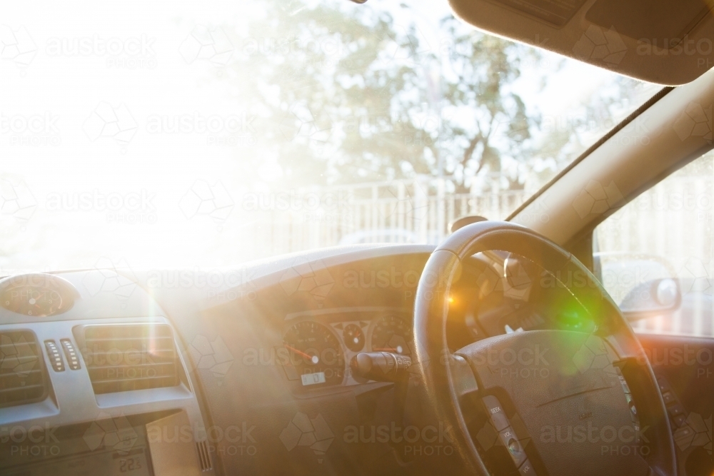 No hands on a car steering wheel with sun flare and copy space - Australian Stock Image