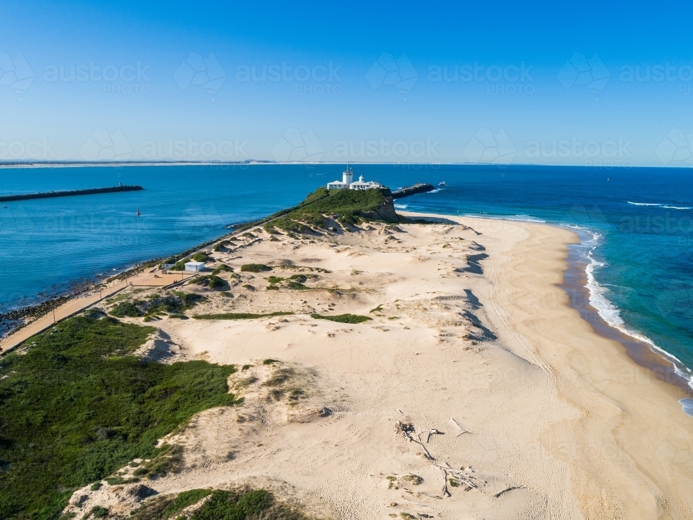 Nobbys Lighthouse and headland to blue ocean where the Hunter River meets the sea - Australian Stock Image