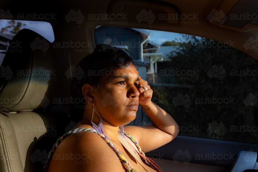 noongar woman sitting in passenger seat with light coming through windscreen - Australian Stock Image