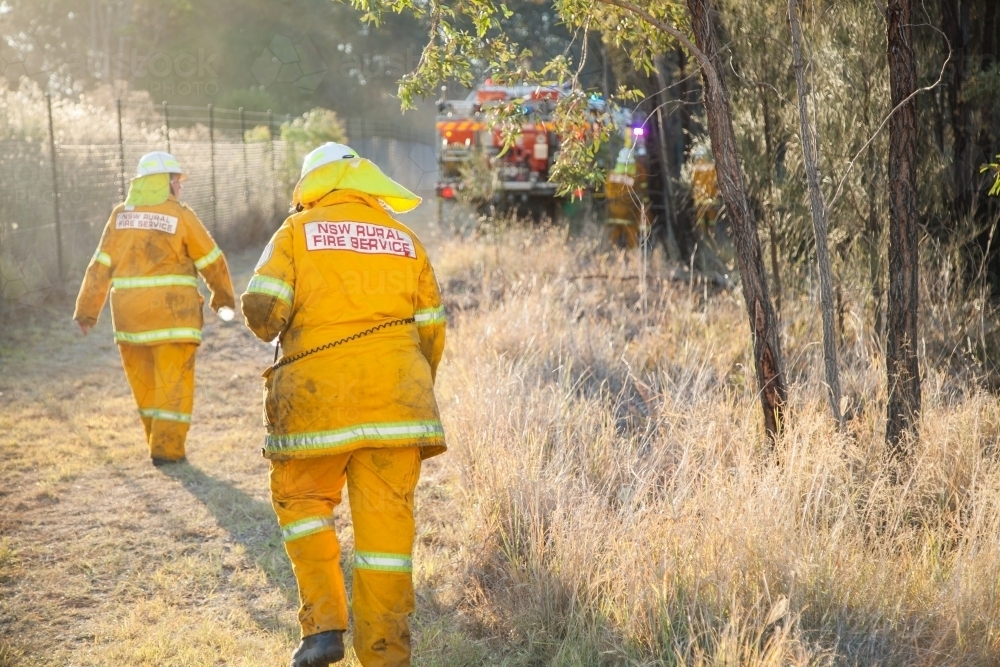 NSW rural fire service volunteer firefighter walking to grass fire in afternoon light - Australian Stock Image