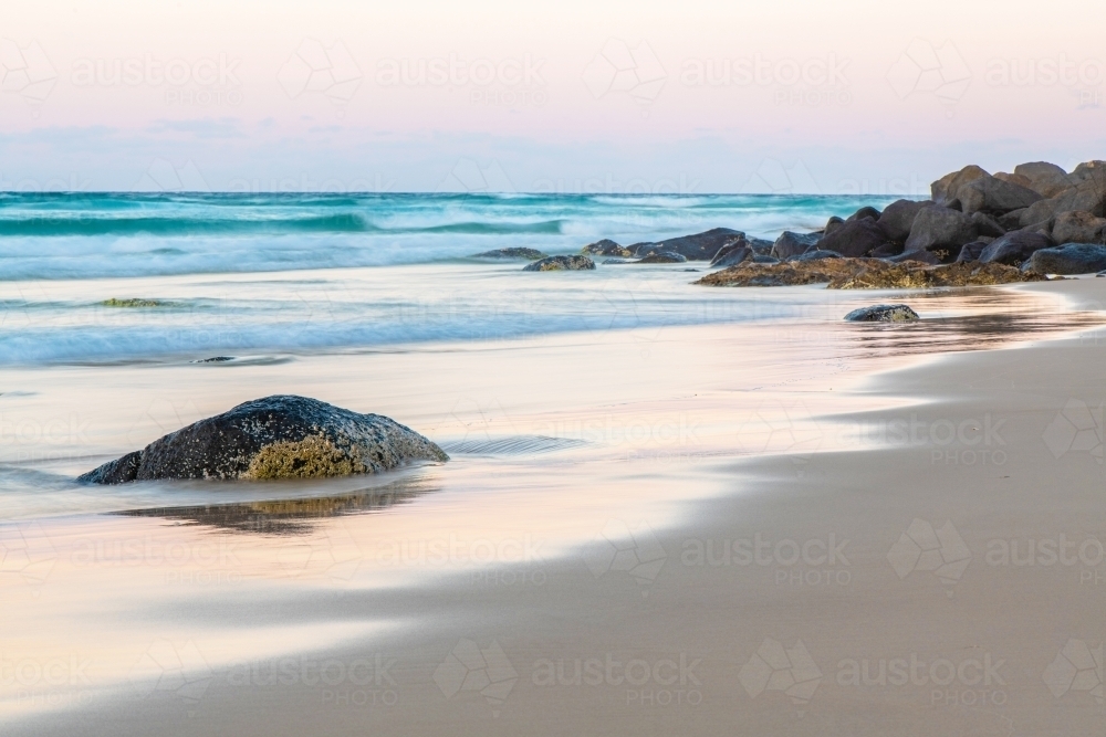 Ocean stone on beach with water reflections. - Australian Stock Image