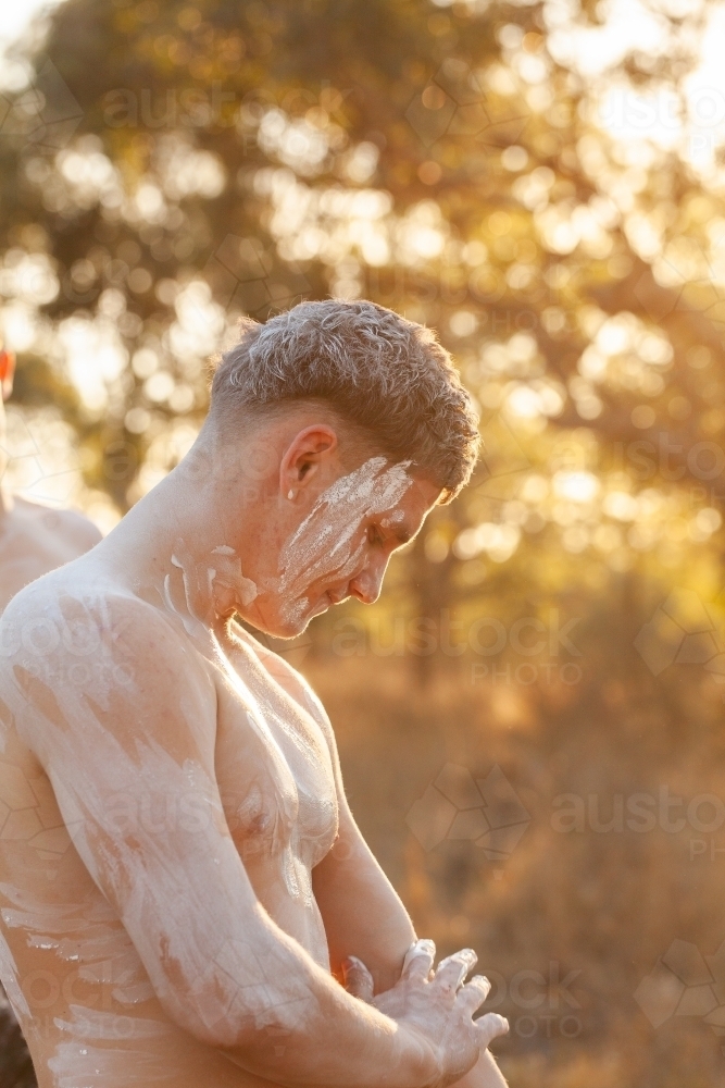 Ochre body paint application on country for storytelling - Australian Stock Image