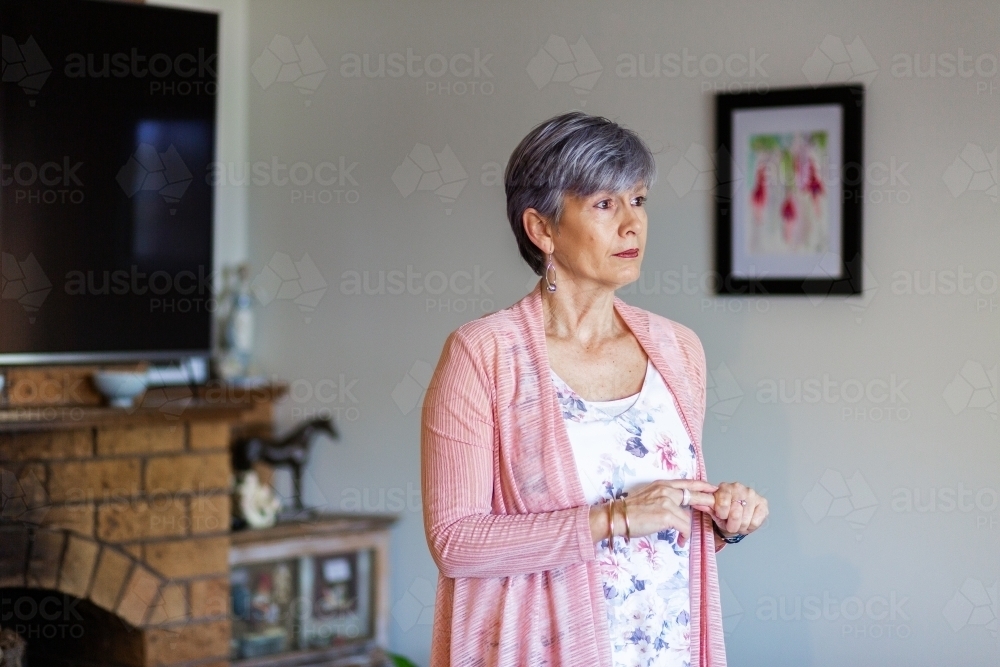 Oder woman looking to the side with copy space in her living room - Australian Stock Image